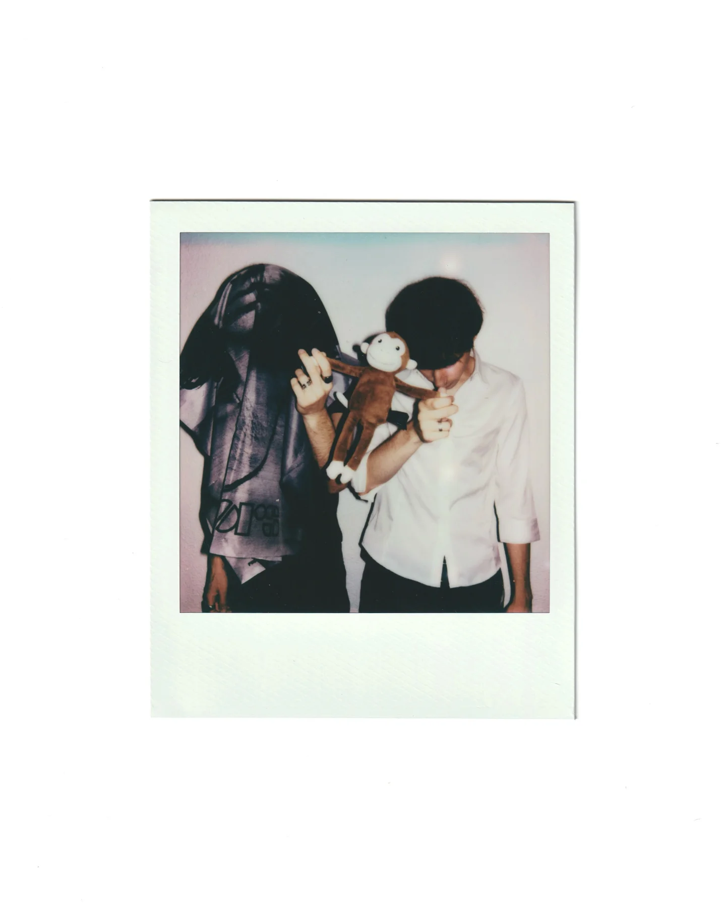 The two members of Dear Lucy on a polaroid, holding a toy monkey